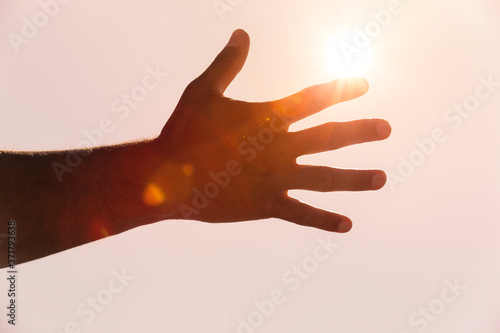 Männerhand im Gegenlicht mit Sonnenstrahlen