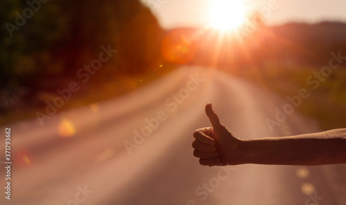 Frauenhand beim Autostopp im Gegenlicht auf Landstrasse