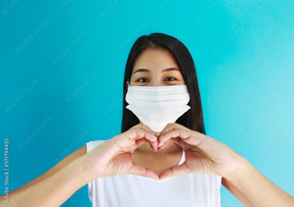 Asian woman with medical mask making hand on heart shape Asian woman with medical mask making hand on heart shape