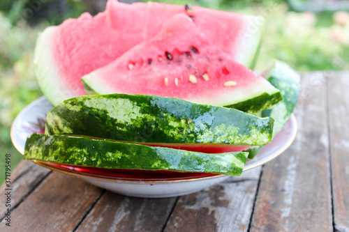 Watermelon ripe in a plate on the table in the garden during the day