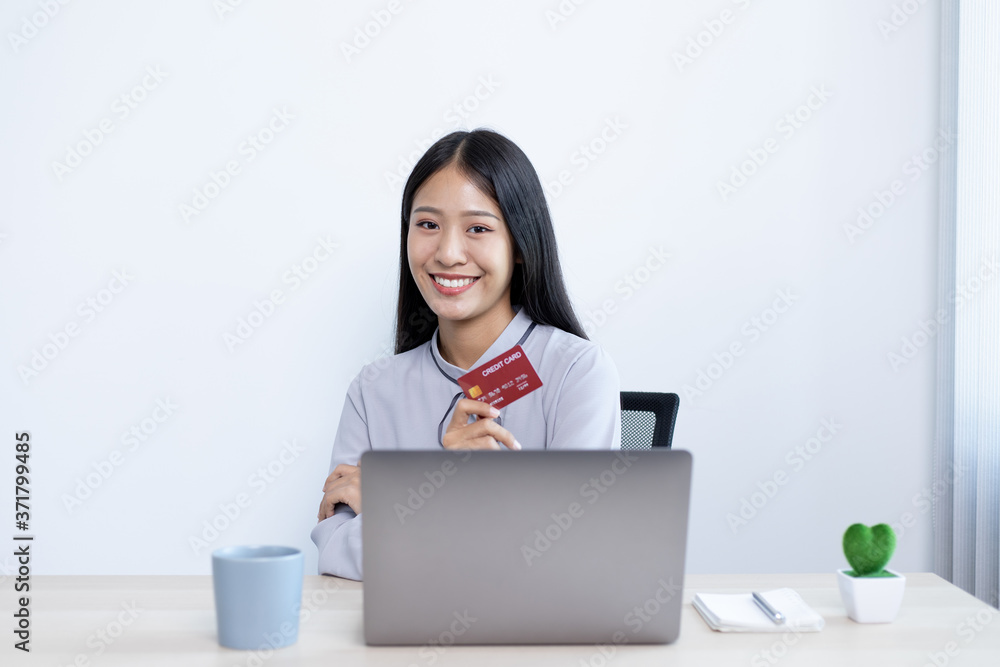 Asian women hold credit cards to shop online on laptops. Asian women hold credit cards to shop online on laptops.