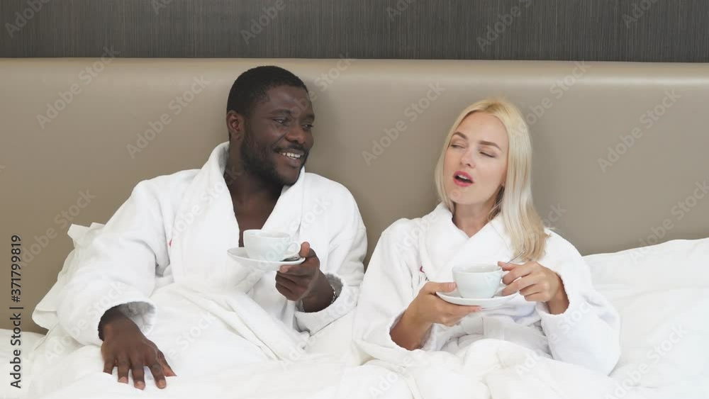 Portrait of beautiful multiethnic couple drinking tea on bed, african man and caucasian woman enjoy weekends, in love. Portrait of beautiful multiethnic couple drinking tea on bed, african man and caucasian woman enjoy weekends, in love.