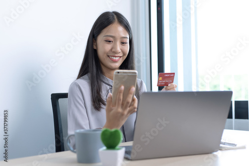 Asian women use their credit card to shop online on their mobile phone.