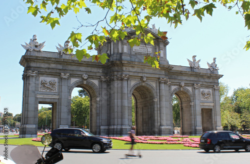 View of the Puerta de Alcala or Alcala Gate, a famous landmark in central Madrid, Spain, with traffic passing.