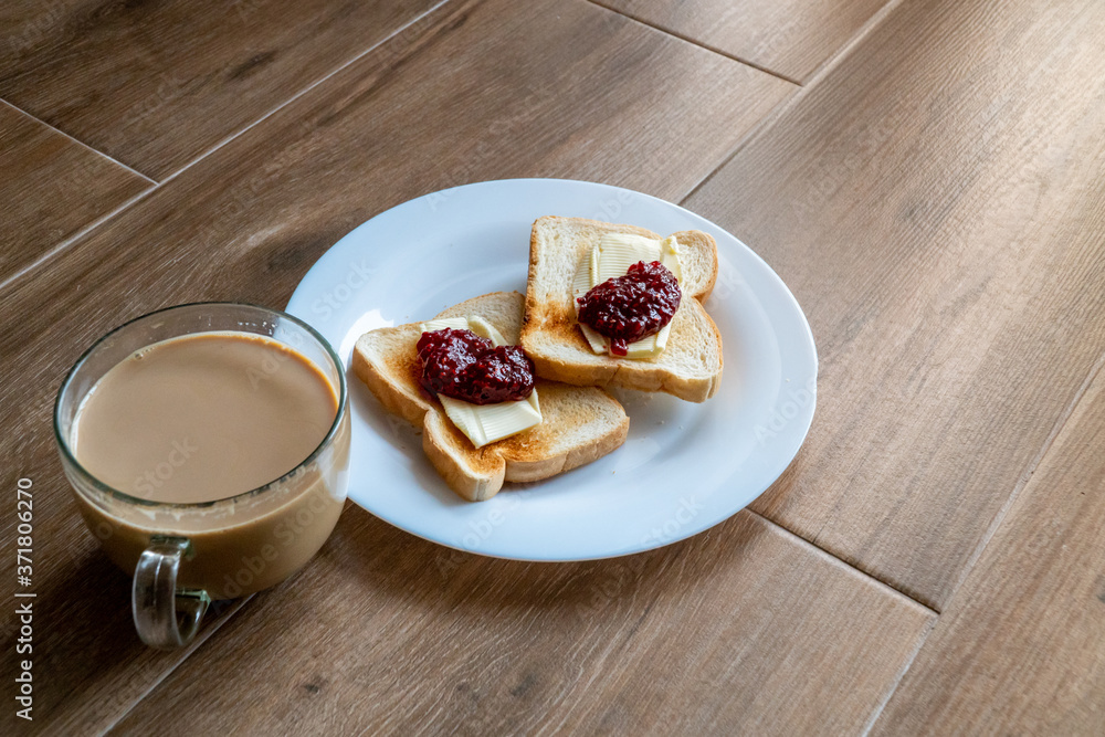 Cup of coffe with milk and two slices of toasted sandwich Bread with Butter and Raspberry. Breakfast with coffee. Side view. Free space for text.