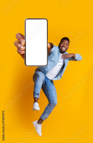 Excited african guy dancing with modern smartphone