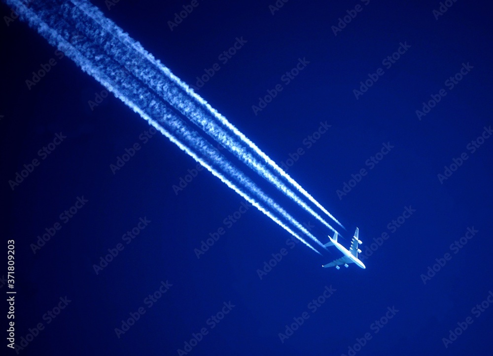 Awesome white jet trails in a dark blue sky and a white airplane
Awesome white jet trails in a dark blue sky and a white airplane