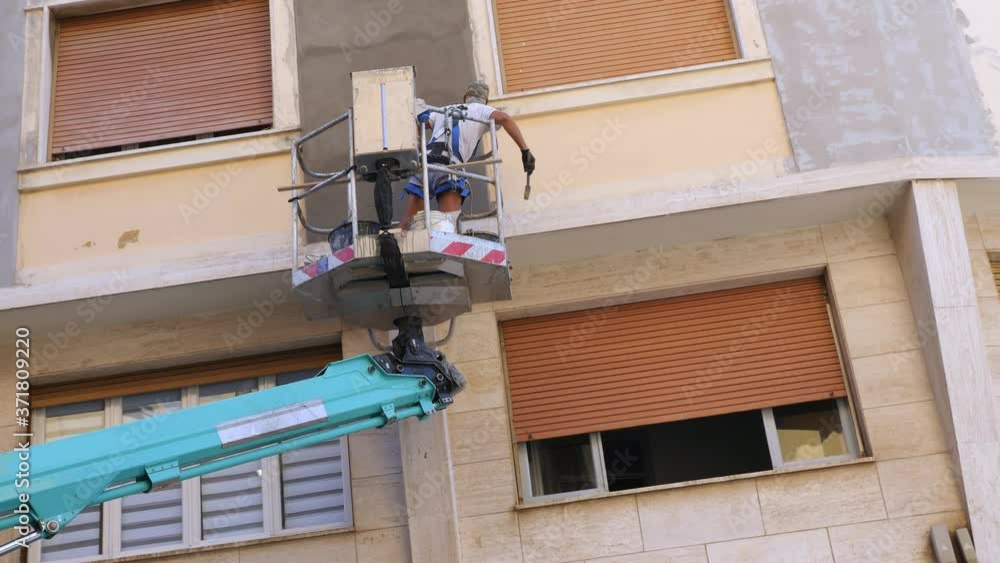 Worker at Work inside a Lift Rack for the Renovation of a Facade of a Building - slow motion Worker at Work inside a Lift Rack for the Renovation of a Facade of a Building - slow motion