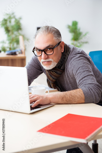 Old male employee working from house during pandemic