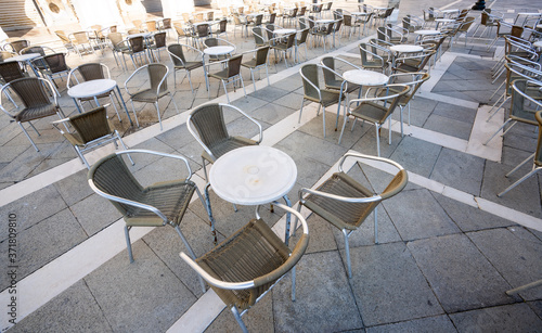 Empty restaurant tables in Venice Italy with grey chairs