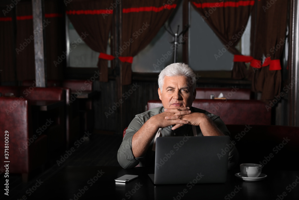 Senior business owner working with laptop in his restaurant