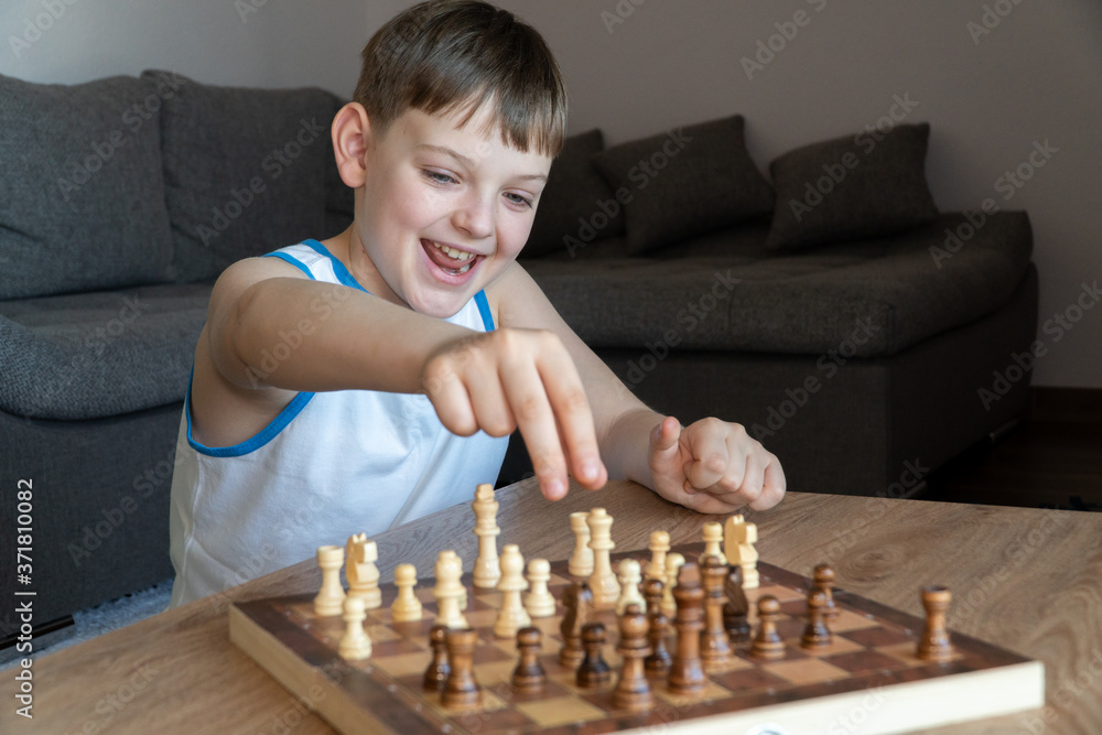 The serious child lost in thought playing chess. Playing board games, on coronavirus quarantine. The child playing chess.