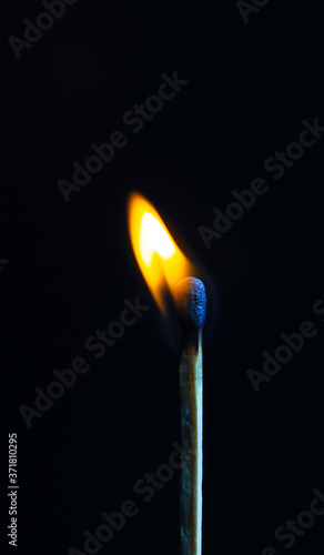 Single matchstick on fire in front of black background.