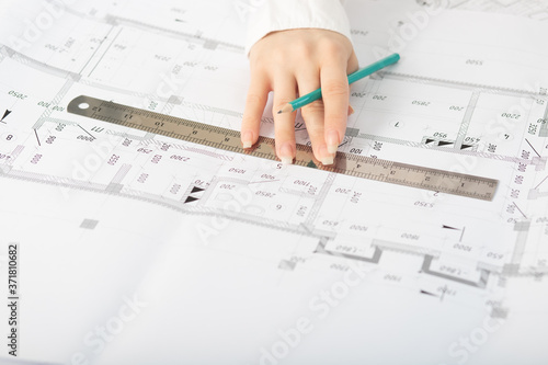 Architect working on blueprint, with architectural project at construction site at office desk in office