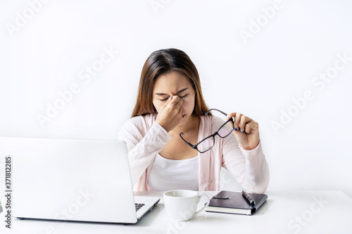 Tired and stressed young asian woman feel pain eyestrain and rubbing her eyes and take off her glasses while sitting at her working place