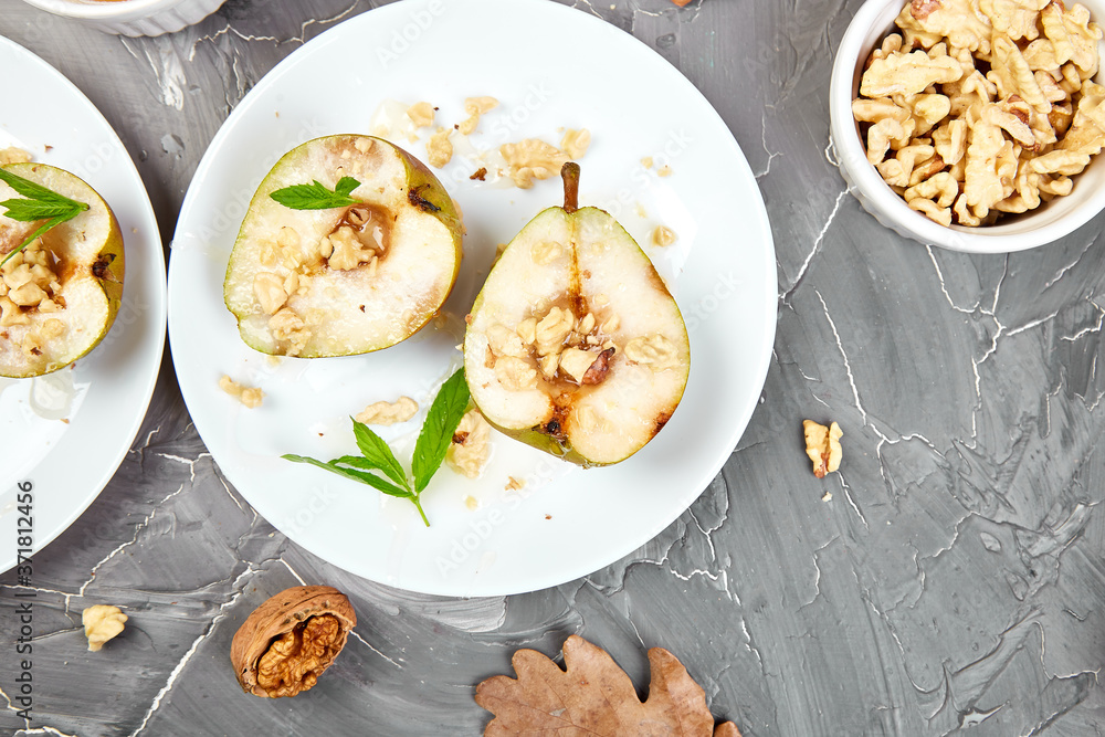 Tasty roast pears with honey and walnuts on grey background table.