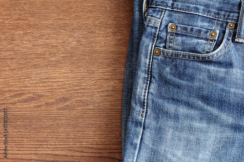 A closeup on a pair of blue jeans on wood with space on the left.