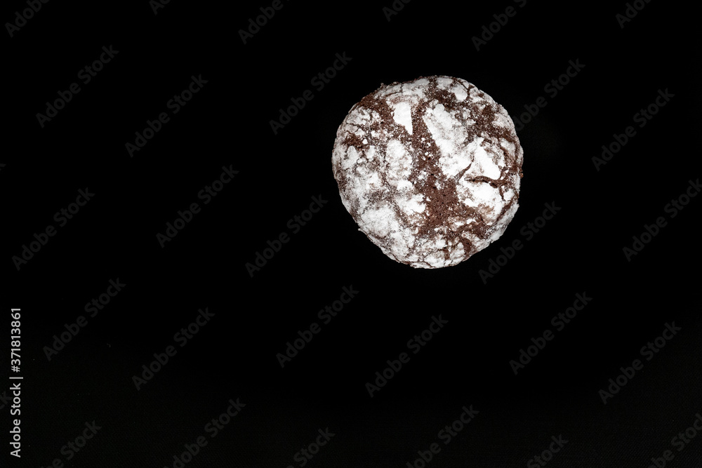 Homemade cookies with chocolate chips with powdered sugar on black background. Freshly baked choco cookie close up. Dark food. Cook at home.