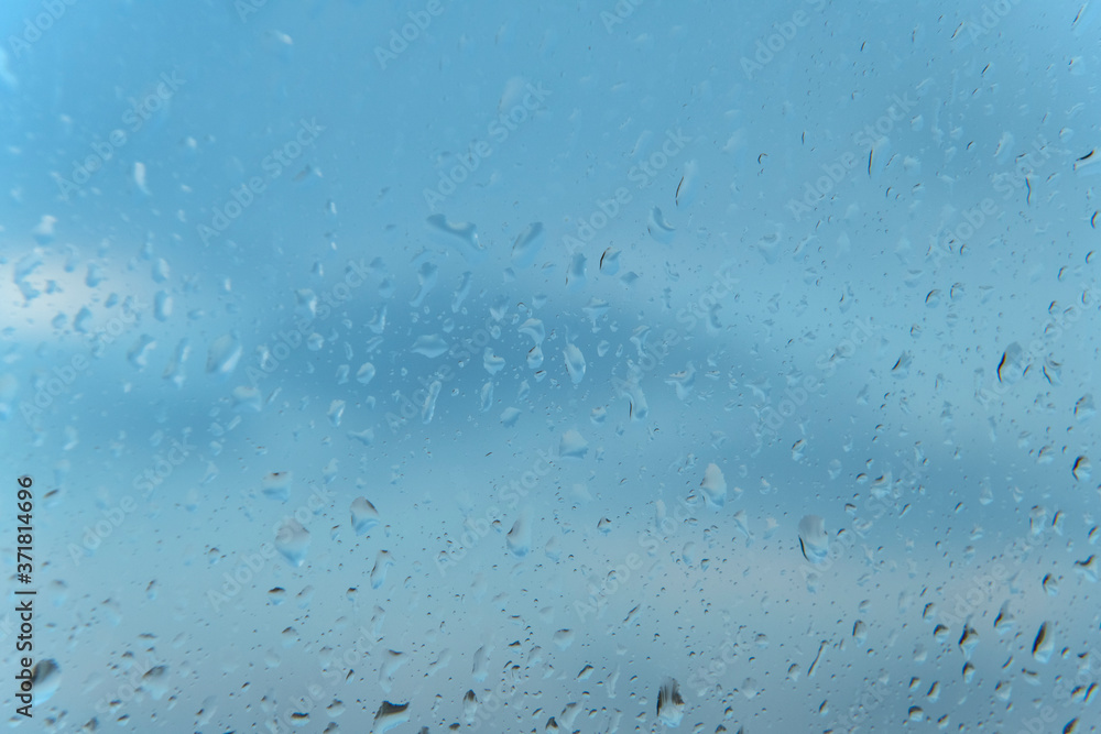 Abstract Rain Water Droplets on Glass Window with a Blue Sky Background Abstract Rain Water Droplets on Glass Window with a Blue Sky Background