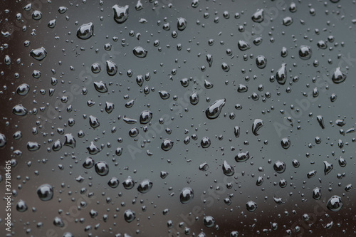 Water droplets on grey / black glass surface. Close up view.