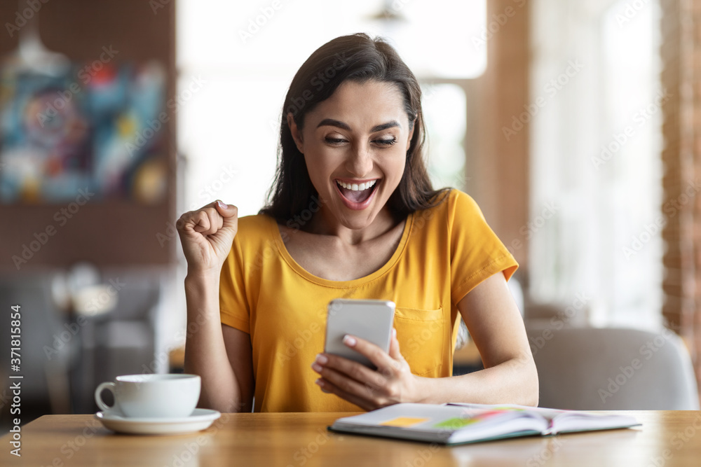 Emotional arab woman looking at smartphone screen Emotional arab woman looking at smartphone screen