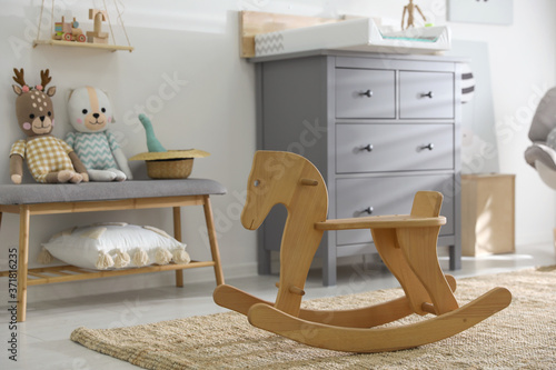 Beautiful baby room interior with toys, rocking horse and modern changing table photo