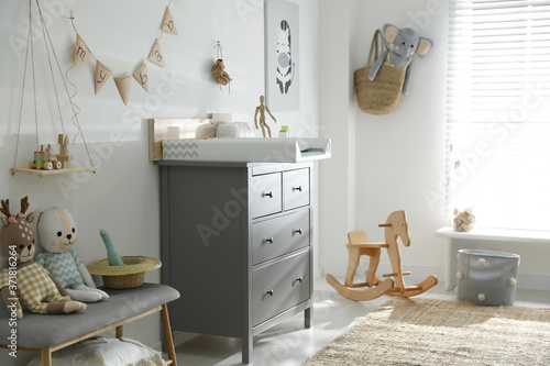 Beautiful baby room interior with toys and modern changing table photo