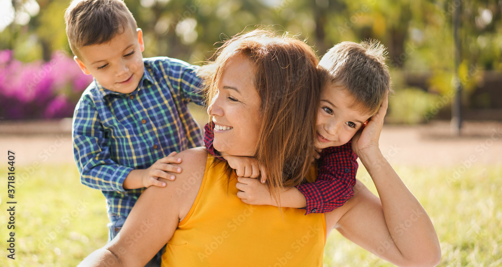 Happy mother enjoy the day with her twin sons in a nature park - Mother have playful time with twin childs - Family, mother and child love