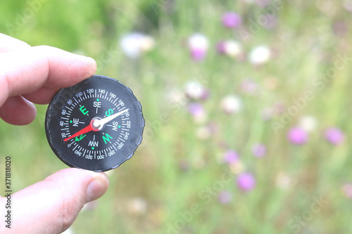 Old classic navigation compass in hand on natural background as symbol of tourism with compass, travel with compass and outdoor activities with compass