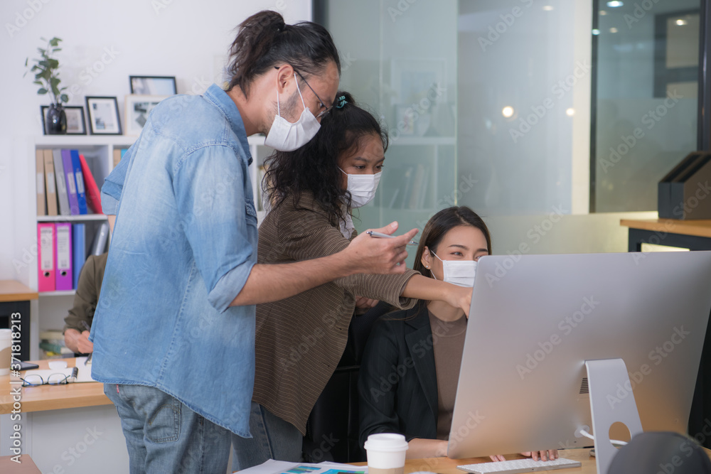 Asian office workers wearing face masks working in new normal office and doing social distancing during corona virus covid-19 pandemic Asian office workers wearing face masks working in new normal office and doing social distancing during corona virus covid-19 pandemic