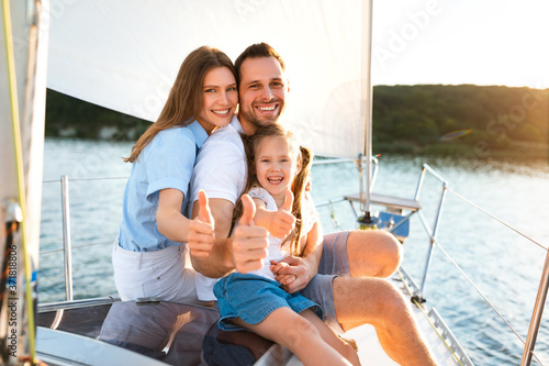 Family Gesturing Thumbs-Up Relaxing On Yacht Posing Sitting On Deck © Prostock-studio