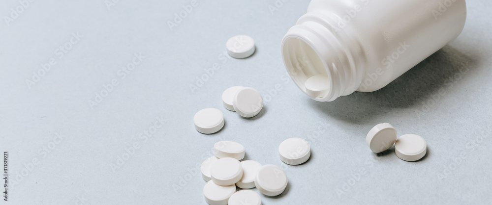 White pills on the doctor's table. Medicine concept. Research on prescribing the dose of medicinal products. Health care or illness. Tablet or drug in hospital or pharmacy. Light blue background. White pills on the doctor's table. Medicine concept. Research on prescribing the dose of medicinal products. Health care or illness. Tablet or drug in hospital or pharmacy. Light blue background.