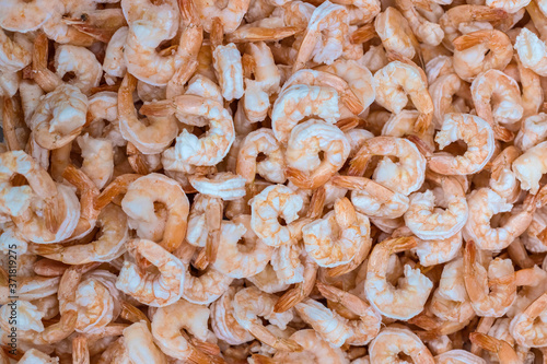 Raw peeled frozen shrimps. Showcase in a supermarket. Top view, background. Selective focus. Blurred.