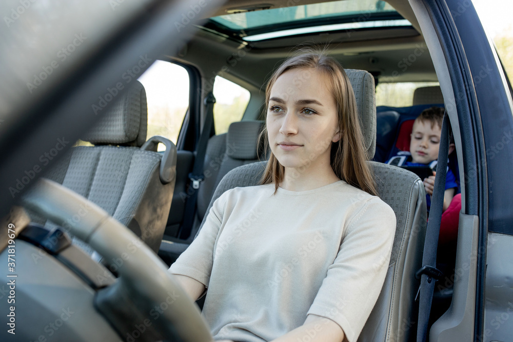 Mother gives the phone little boy sitting in a car seat. Safety of transportation of children. Mother gives the phone little boy sitting in a car seat. Safety of transportation of children.