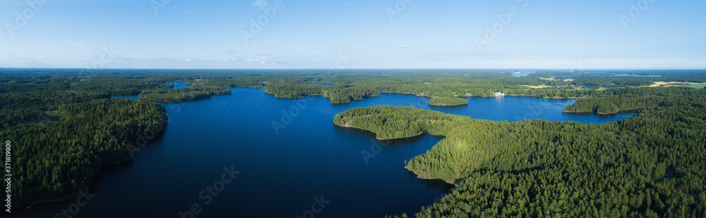 Aerial view of beautiful lake with islands and green forests in Finland on a sunny summer day. Drone photography