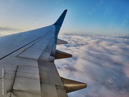 Clouds and sky as seen through window of an aircraft with airplane's wing