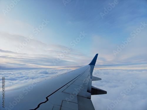 Clouds and sky as seen through window of an aircraft with airplane's wing