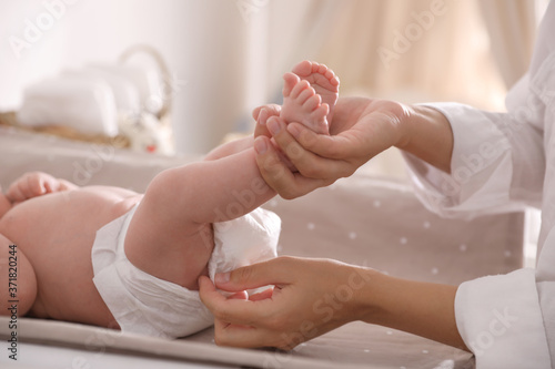 Papier peint Mother changing her baby's diaper on table, closeup