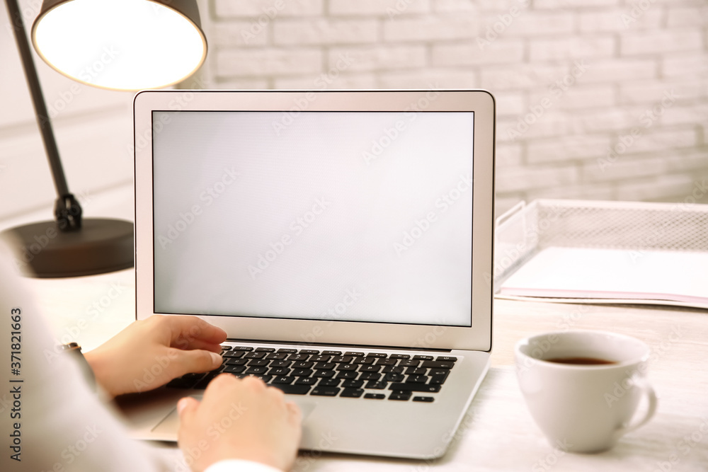 Fototapeta premium Woman working with modern laptop at white table, closeup. space for design