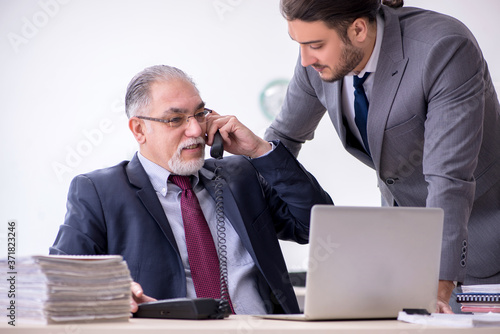 Old boss and his young assistant working in the office