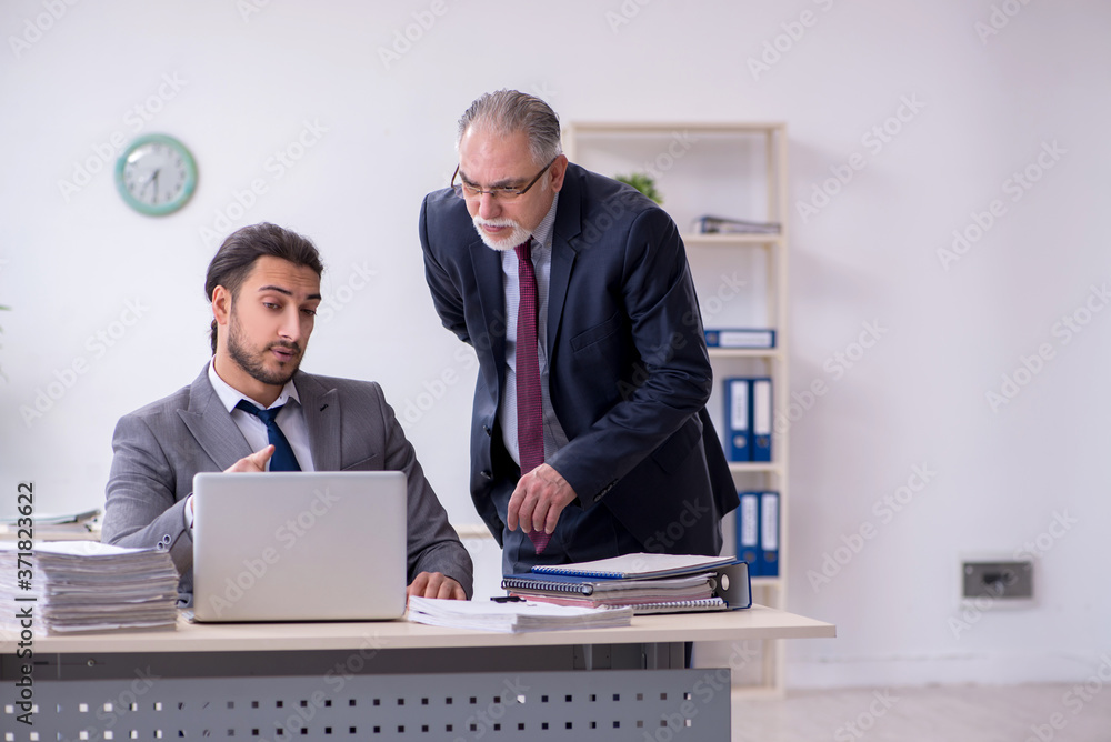Old boss and his young assistant working in the office Old boss and his young assistant working in the office