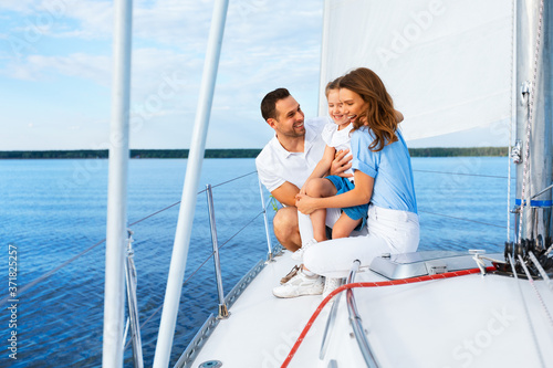 Joyful Family Riding Yacht Sailing In Sea Enjoying Summer Vacation