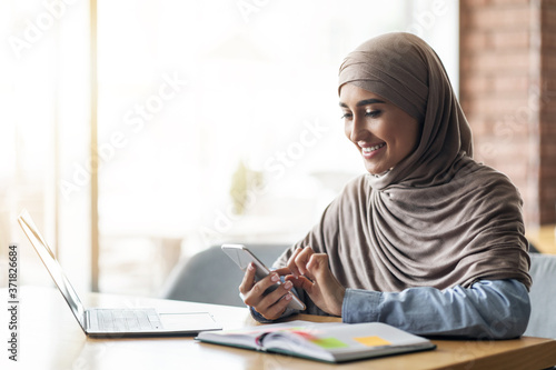 Arab woman freelancer working at cafe, chatting with clients