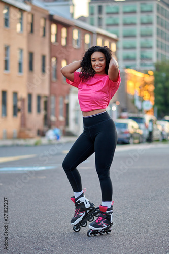Beautiful young woman roller blades in the city wearing pink mesh shirt