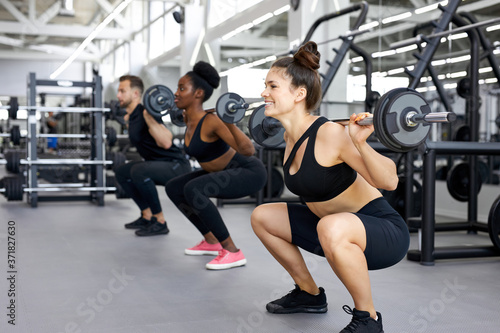sportive people, multiethnic group perform exercises with heavy weights in gym. young diverse man and women workout, have muscular body © alfa27