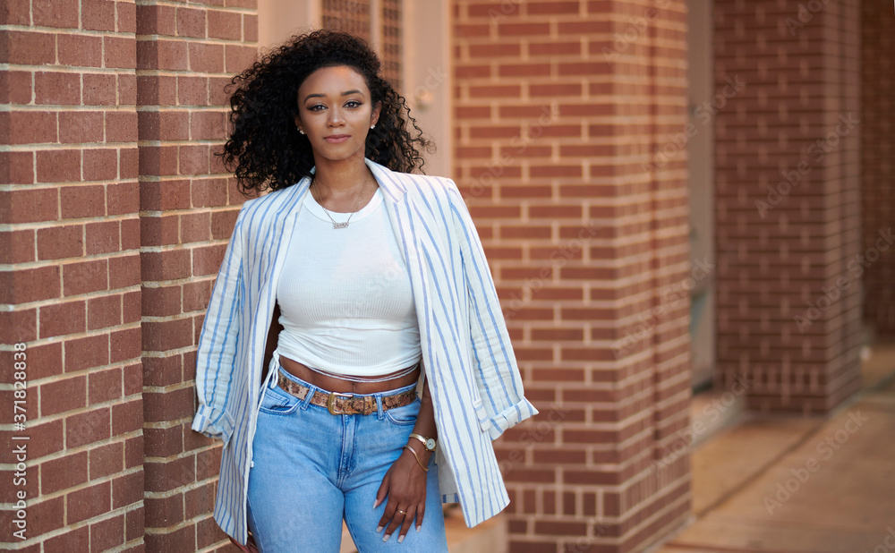 Stunning young black woman poses near brick wall wearing blue jeans, white  shirt and blazer - fashion and business casual Stock Photo | Adobe Stock