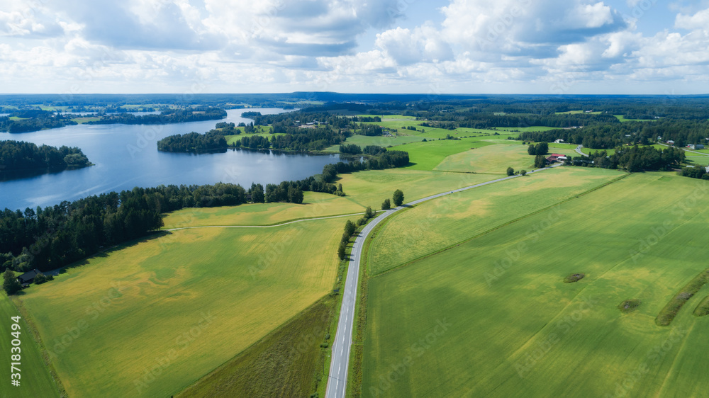 View of agricultural fields, lakes and road in summer, Finland. Aerial view. Drone view.
