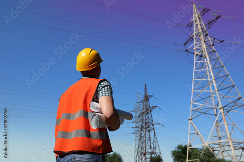 Professional electrician with papers near high voltage tower
