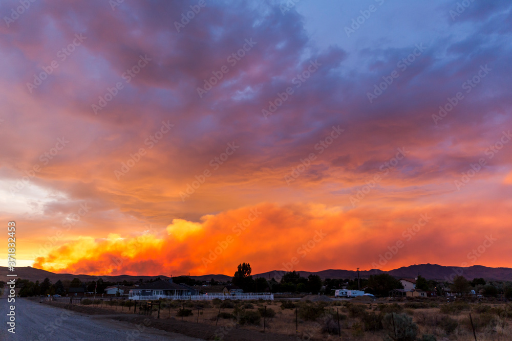 Brilliantly colored sunset in the desert over a community during a wildfire with smoke in the air