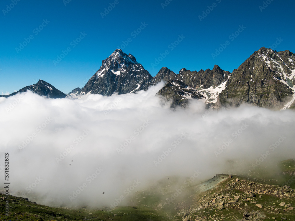 Mountain landscape on the Alps, rocky mountains at high altitude, moody sky green valley and hiking paths for tourism summer vacation